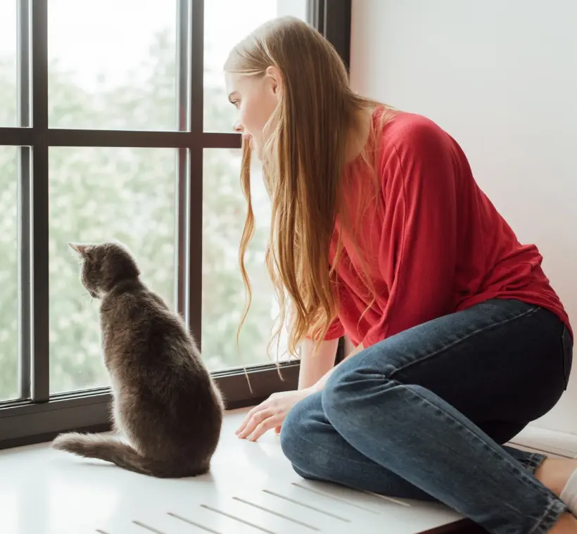 Woman and cat looking through window